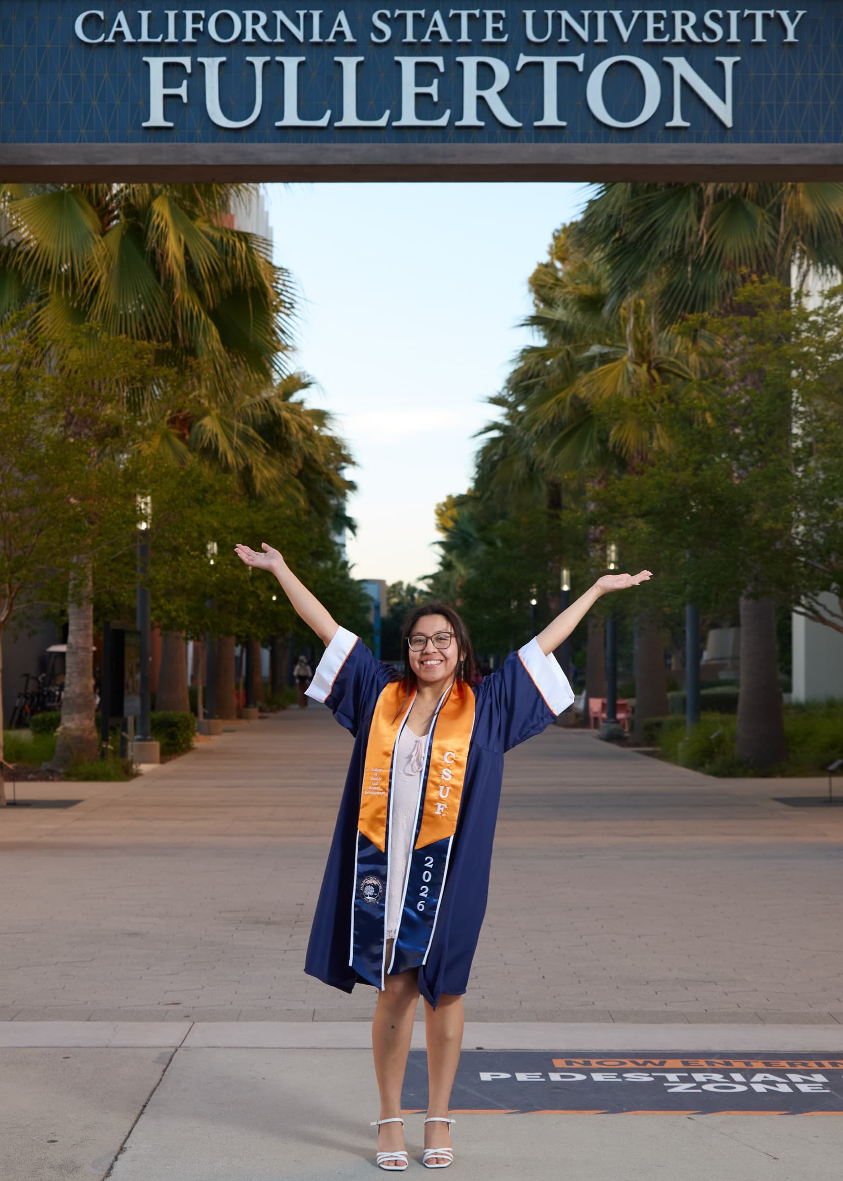 Grad celebrating under the Cal State Fullerton arch